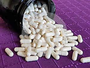 White creatine tablets on purple background