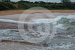 WHITE CRESTED WAVES BREAKING ON THE BEACH AGAINST BACKWASH photo