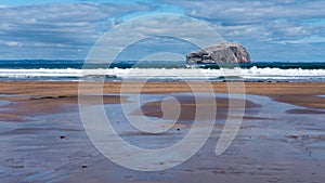 White crested waves rolling on the beach with Bass Rock in the b