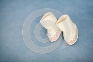 White crochet baby booties on blue background, closeup