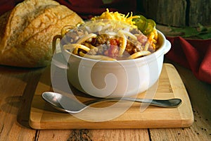 White crock of chunky hearty chili on wood photo