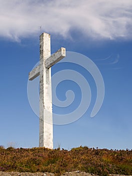 White cross against blue cloudy sky background. Concept catholic religion