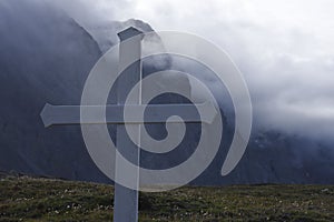 White cross in front of foggy mountains