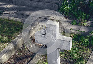 White cross on the grave in the old cemetery. Small plaster figures of angels on the cross