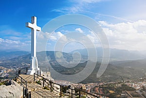 A white cross over Jaen town at the mountain, a symbol of the town with Sierra Magina mountains on background on sunny day