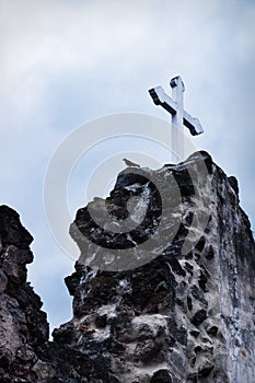 White cross on stone ruins with dramatic sky in Hermano Pedro, Antigua, Guatemala photo