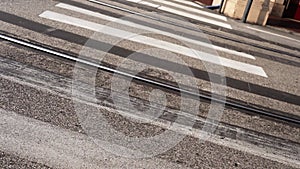 White crosswalk across parallel tram rails on asphalt road