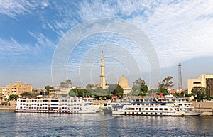 White cruise ships on the Nile in front of the city of Luxor in sunshine.