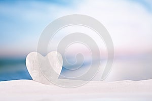 White crystal heart on white sand beach