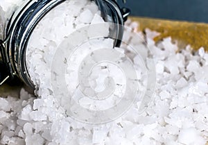 White crystals sea salt in glass bottles on table backg