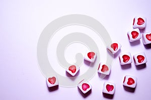 White cubes with red hearts. The 14th of February. White background and cubes side view. Dice beads. White background