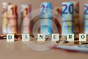 Cubes spelling Dinero in front of Spanish dinero bills and coins on the table photo