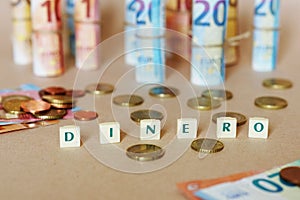 Cubes spelling Dinero in front of Spanish dinero bills and coins on the table