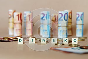 Cubes spelling Dinero in front of Spanish dinero bills and coins on the table photo