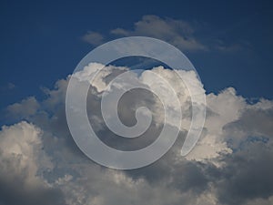 White cumulus in the blue sky partially obscured by the gray nimbostratus