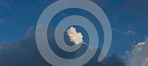 White cumulus cloud among dark rain clouds