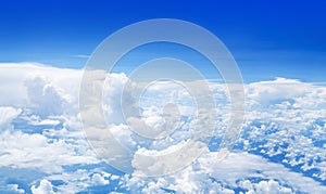 White cumulus clouds on clear blue sky background, aerial cloudscape panoramic view from airplane, high azure skies panorama