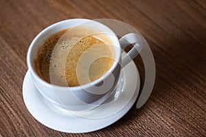 White cup of aromatic coffee on a wooden table