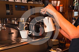 White cup being filled with decaf coffee in a cafe, a barista working