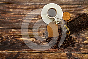 White cup with black coffee and coffee grains on a wooden table background. View from above. Place for text.