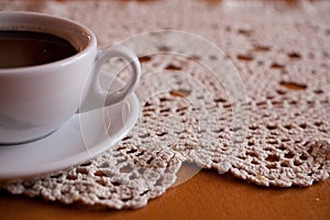 White cup with black coffee on a hand-made tablecloth