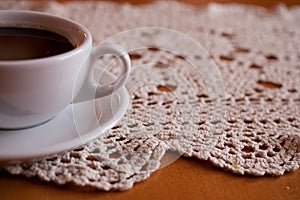 White cup with black coffee on a hand-made tablecloth