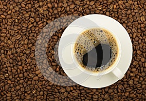 White cup of black coffee on roasted beans