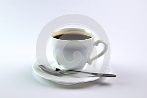White cup of black coffee and a spoon on a white background