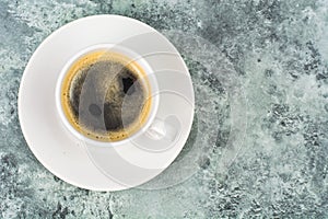 White cup with black espresso coffee on blue and gray background