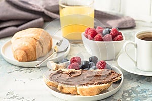 White cup of black tea with croissant or toasts with peanut butter, chokolate paste , jelly or jam on white wooden table, Breakfas