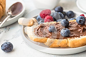 White cup of black tea with croissant or toasts with peanut butter, chokolate paste , jelly or jam on white wooden table, Breakfas