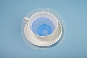 White cup with blue liquid on blue background. Blue Monday.