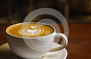 White cup of cappuccino with latte art on wooden background at coffee cafe