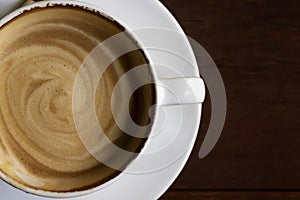 White cup of cappuccino with latte on wooden background at coffee cafe