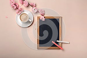 White cup with cappuccino, sakura flowers, chalk board on a past