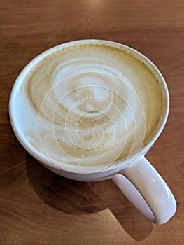 White cup of Cappuccino with swirl in foam photo