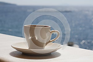 White cup with coffee on the background of the sea. Sunny day, vacation at sea. Enjoyment moment. Enjoying a cup of