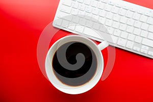 White cup of coffee on a bright red background. View from above with a keyboard. Menu, packaging design, poster, invitation card