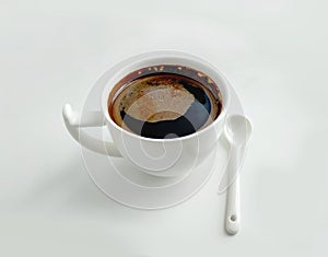 White cup of coffee and white ceramic spoon on a white background