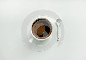 White cup of coffee and white ceramic spoon on a white background