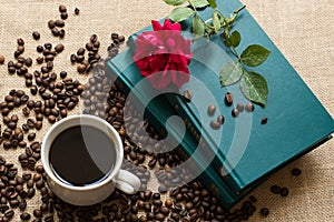 White cup of coffee, with coffee beans on books background