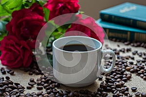 White cup of coffee, with coffee beans on books background