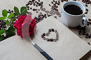 White cup of coffee, with coffee beans and sketchbook