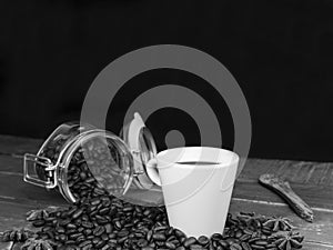 White cup of coffee and coffee beans on wooden table.Black and white photography ,concept of rustic coffee on dark background with
