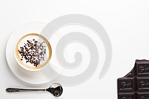 White cup of coffee with dark chocolate on black background.