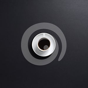 A white cup of coffee on a dark grey desk background