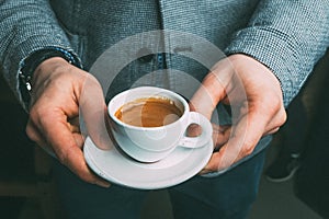 White cup of coffee in hands