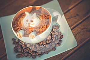 White cup of coffee latte with cute cat shape latte art milk foam on wood table