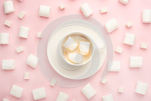 White cup of coffee with marshmallows, and marshmallows, and sugar cubes around on a pink background. Possibility to use as