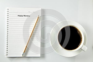 White cup of coffee morning on wooden table with notebook